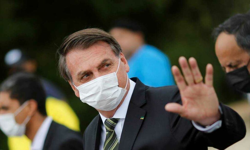 x88069605 Brazils President Jair Bolsonaro wearing a protective mask gestures as he walks to the.jpg.pagespeed.ic .NXiR1fZbYi Proposta de socorro emergencial a estados e municípios aguarda sanção do presidente Jair Bolsonaro